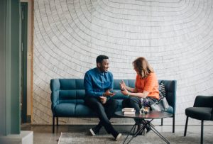 Canapé bleu avec un homme et une femme en train de discuter durant une pause