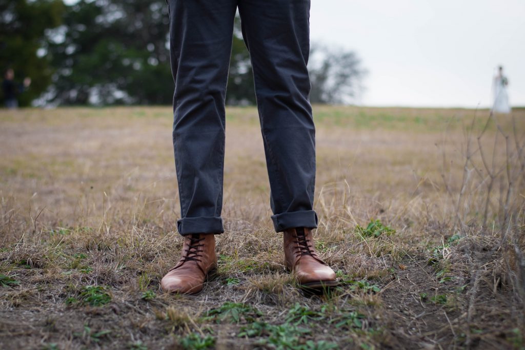 vue sur les jambes d'un homme portant un pantalon gris foncé et des bottines marron